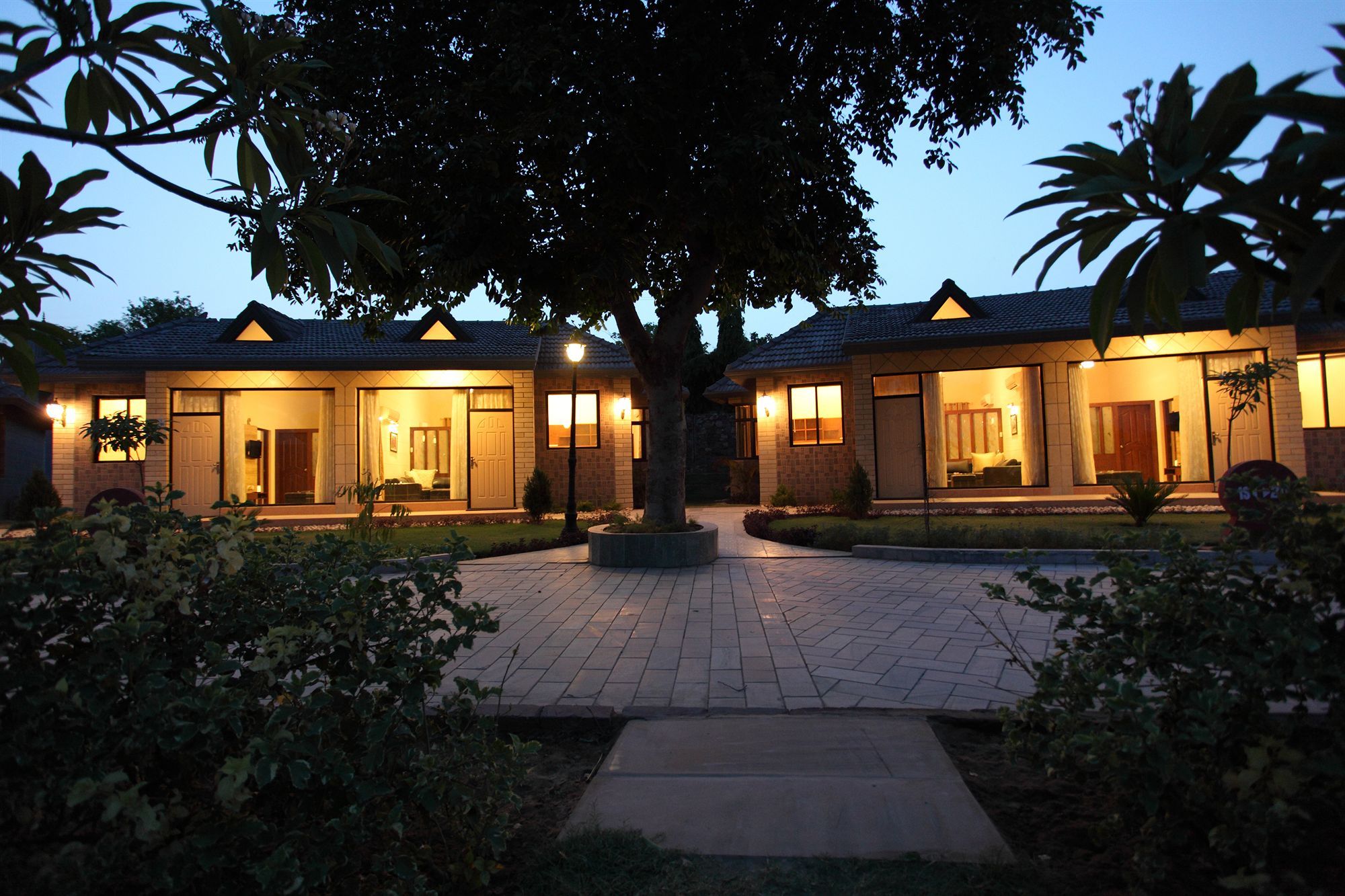 A two-story building with a paved entrance and a tree in the center.