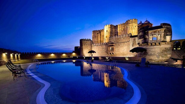 A historic castle with a large reflective pool in the foreground. - Fort Khejarla (Bilara)