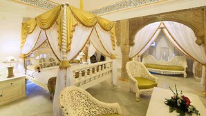 A luxurious bedroom with a four-poster bed, ornate chairs, and a decorative table. - Fort Khejarla (Bilara)