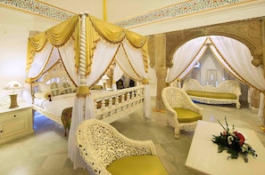 A luxurious bedroom with a four-poster bed, ornate chairs, and a decorative table. - Fort Khejarla (Bilara)