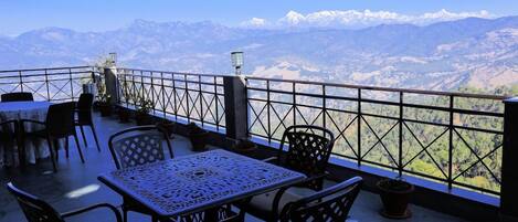 A terrace with a table and chairs, overlooking a mountainous landscape.