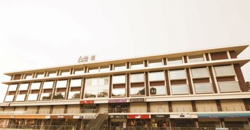 Un edificio de varios pisos con fachada plana, ventanas amplias y diversos comercios en la planta baja.