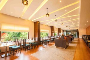 Un restaurante espacioso con techos altos, iluminación colgante moderna y vistas a zonas verdes.