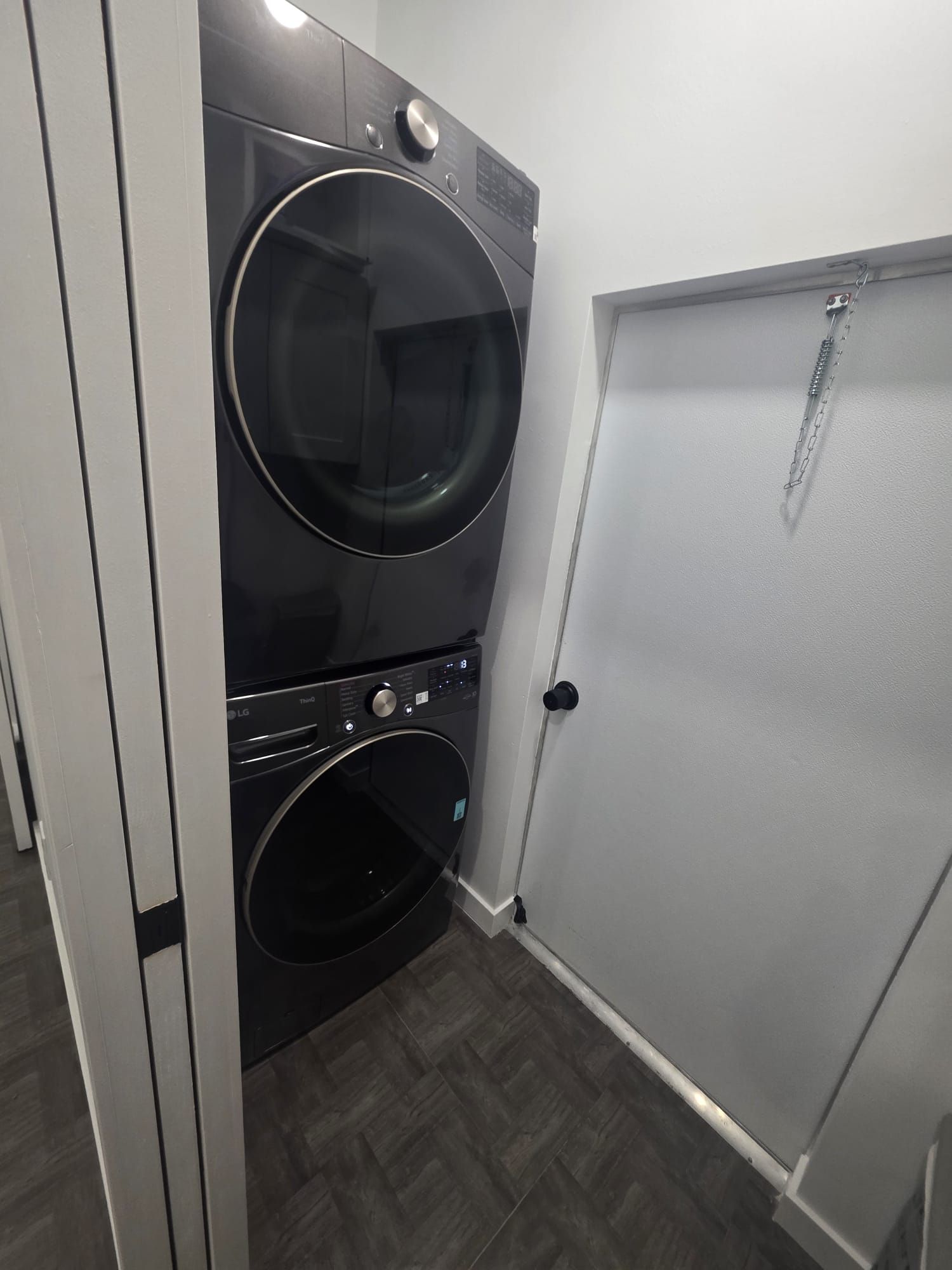 A laundry room with two stacked washing machines and a closed door.