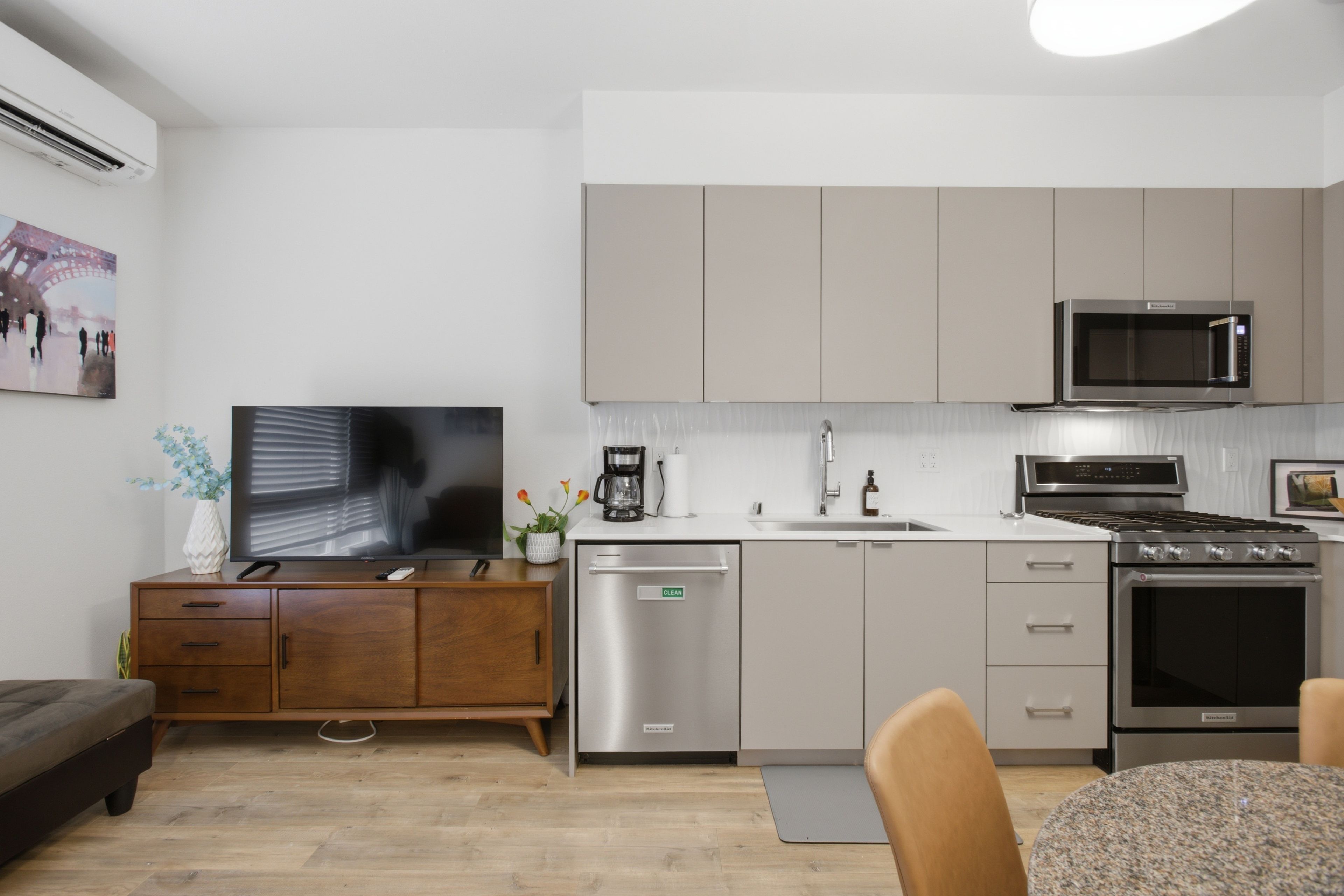 A modern kitchen with a dishwasher, microwave, stove, and a dining area with a table and chairs.