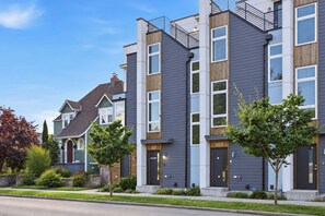A modern multi-story residential building with a grey facade, large windows, and a visible address number. - Ballard Bright Modern Townhome w/ Rooftop Deck (Seattle)