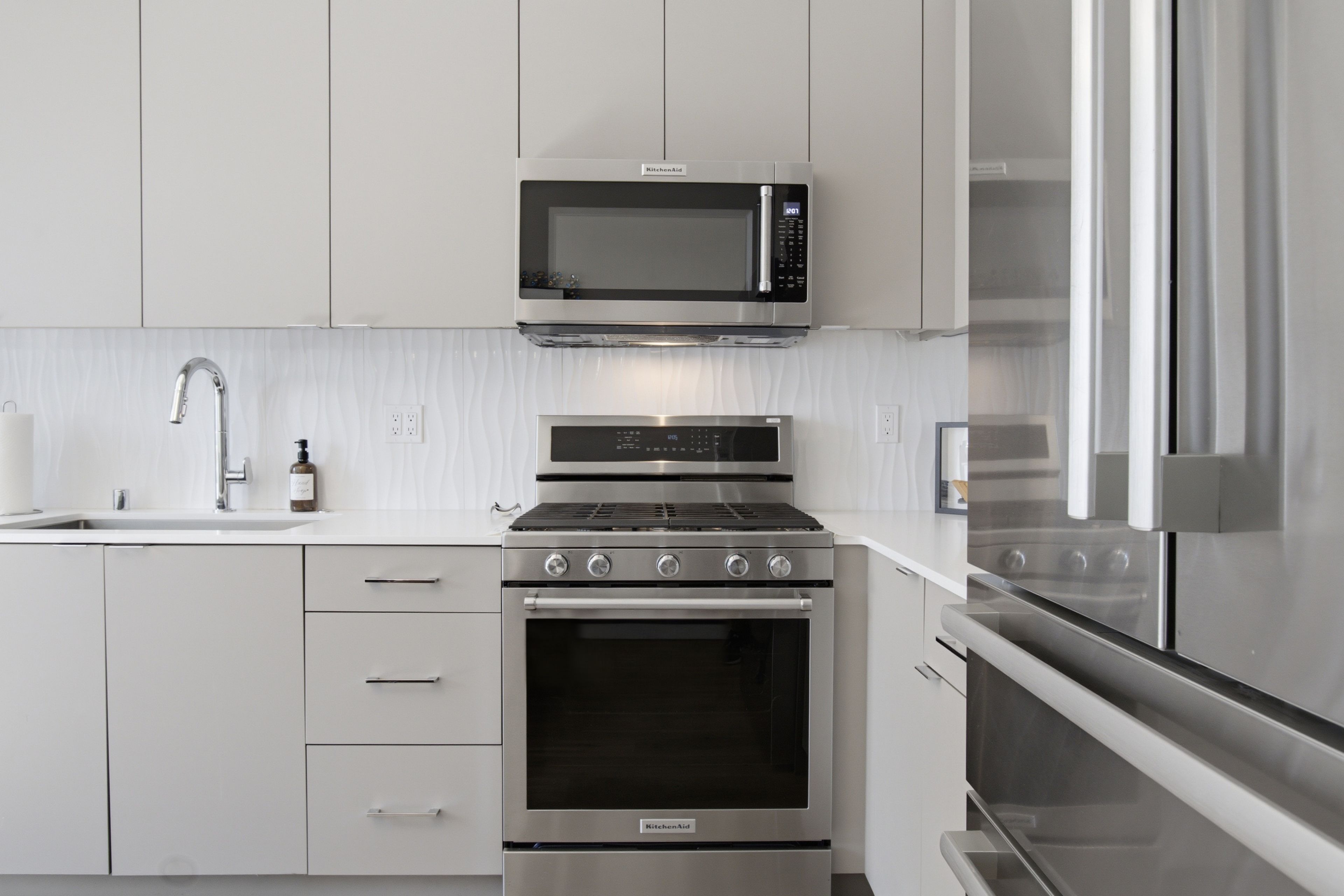 A modern kitchen with stainless steel appliances, including a microwave, oven, and refrigerator.