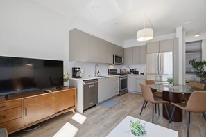 A modern kitchen with a built-in oven, microwave, and dishwasher. There is a dining area with a table and chairs. - Ballard Bright Modern Townhome w/ Rooftop Deck (Seattle)