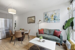 A modern living space with a dining area, kitchen, and a large window with plants. - Ballard Bright Modern Townhome w/ Rooftop Deck (Seattle)