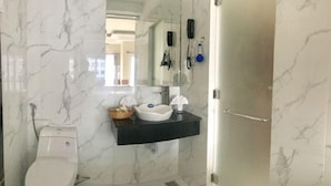 Un bany amb vàter, un lavabo amb mirall a sobre i zona de dutxa.