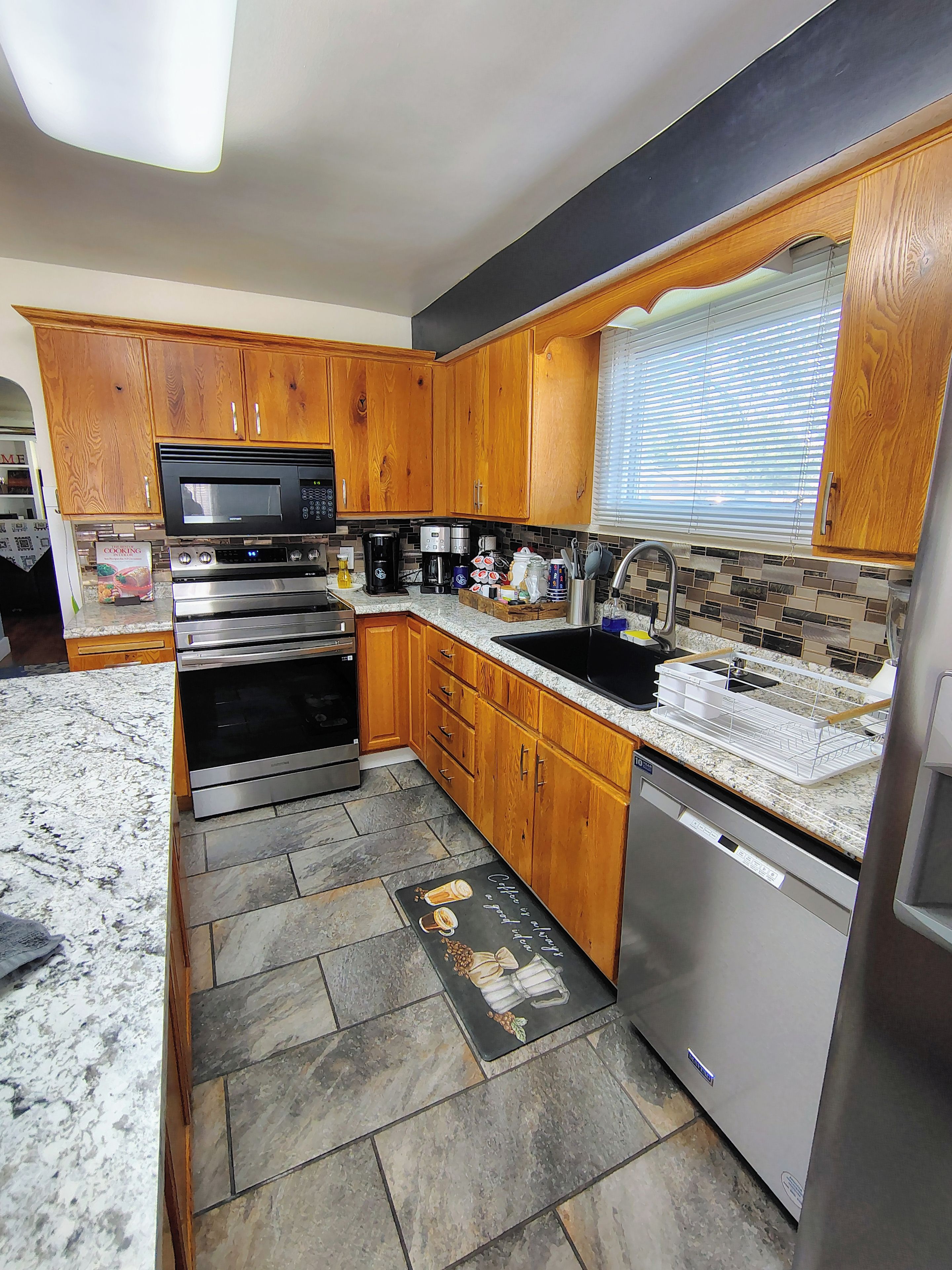 A modern kitchen with wooden cabinets, stainless steel appliances, and a tiled backsplash.
