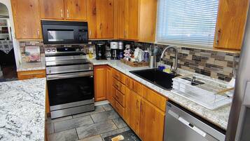 A modern kitchen with wooden cabinets, stainless steel appliances, and a tiled backsplash.