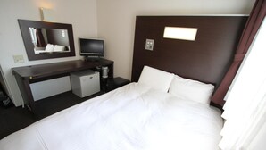 A hotel room with a bed, a desk with a computer, a TV, and a small refrigerator. - Green Rich Hotel Hiroshima (Hiroshima)