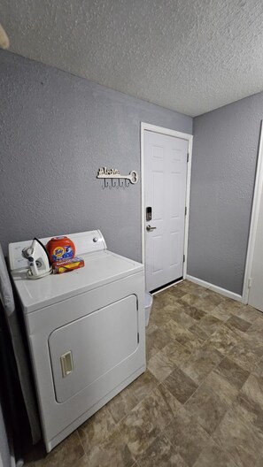 A laundry room with a washing machine, an iron, and a door with a key hook. - Comfy 3BD Dog Friendly home! (Colorado Springs)