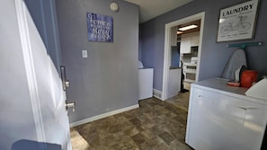 A laundry room with a sign indicating laundry services, a washing machine, a dryer, and a countertop with a red mug. - Comfy 3BD Dog Friendly home! (Colorado Springs)