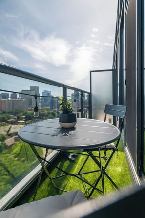Ein Balkon mit rundem Tisch, einem Blumentopf und einem Stuhl.