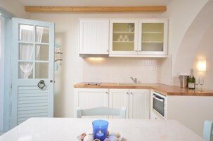 A kitchen with white cabinets, a wooden countertop, a sink, a stove, and a microwave.