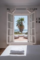Un dormitorio abierto con cama, vistas al mar y una palmera.
