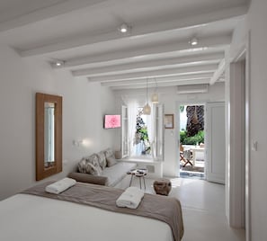 A bedroom with a large bed, a mirror, a TV, and a window with a view of the outdoors. - Kavos Boutique Hotel Naxos (Naxos)