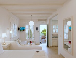 Quarto de hotel com cama, sofá, área de refeições e cozinha.