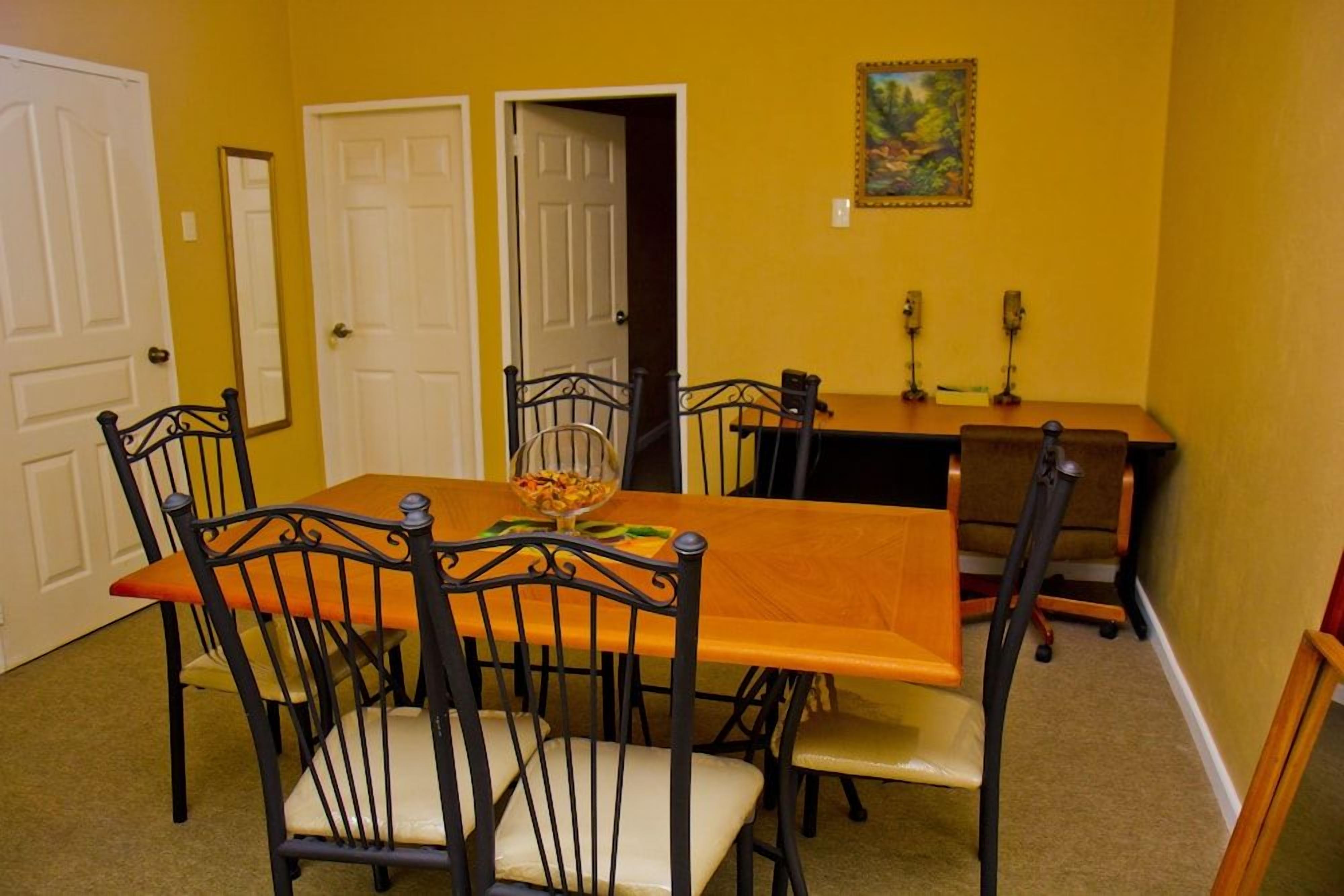 A dining area with a rectangular table, six chairs, and two doors.