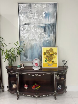 A dark wooden console table with decorative items, a framed abstract painting, and a potted plant.
