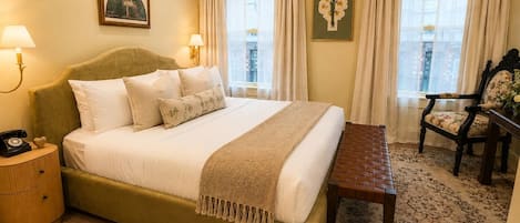 A bedroom with a bed, bedside tables, a bench, and a chair.