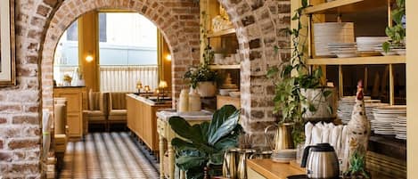 A restaurant with brick walls, checkered flooring, and hanging pendant lights.