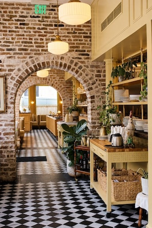 A restaurant with brick walls, checkered flooring, and hanging lamps. - Ethan's Room at Keystone Hotel - 207 (Savannah)