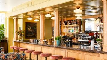 A bar area with stools, a counter, and shelves of bottles.