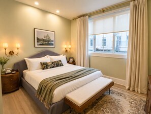 A neatly arranged bedroom with a large bed, bedside lamps, a window with curtains, and a framed picture on the wall. - Uncle Jack's Room at Keystone - 204 (Savannah)