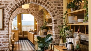 Restaurante com paredes de tijolo, chão xadrez e luminárias penduradas.