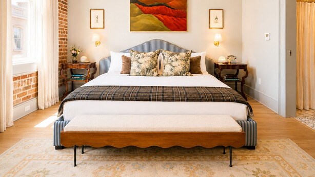 Quarto com cama grande, duas mesas de cabeceira, quadro na parede e janela com cortinas.