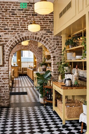 A restaurant interior with brick walls, a checkered floor, and a central archway leading to the dining area. - Aunt Rachel's Room at Keystone - 203 (Savannah)