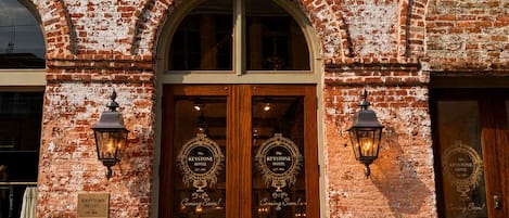 A brick building with a double wooden door labeled 'The Keystone Hotel' and 'Lobby Entrance.' There are two potted plants on either side of the entrance.