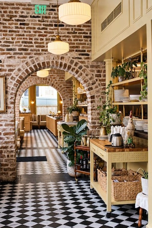 A restaurant with brick walls, checkered flooring, and hanging pendant lights. - Grandma's Room at Keystone | Downtown Savannah (Savannah)
