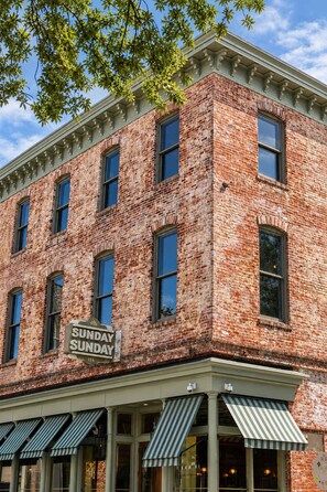 A brick building with a sign reading 'Sunday Sunday 116' and awnings over the entrance.