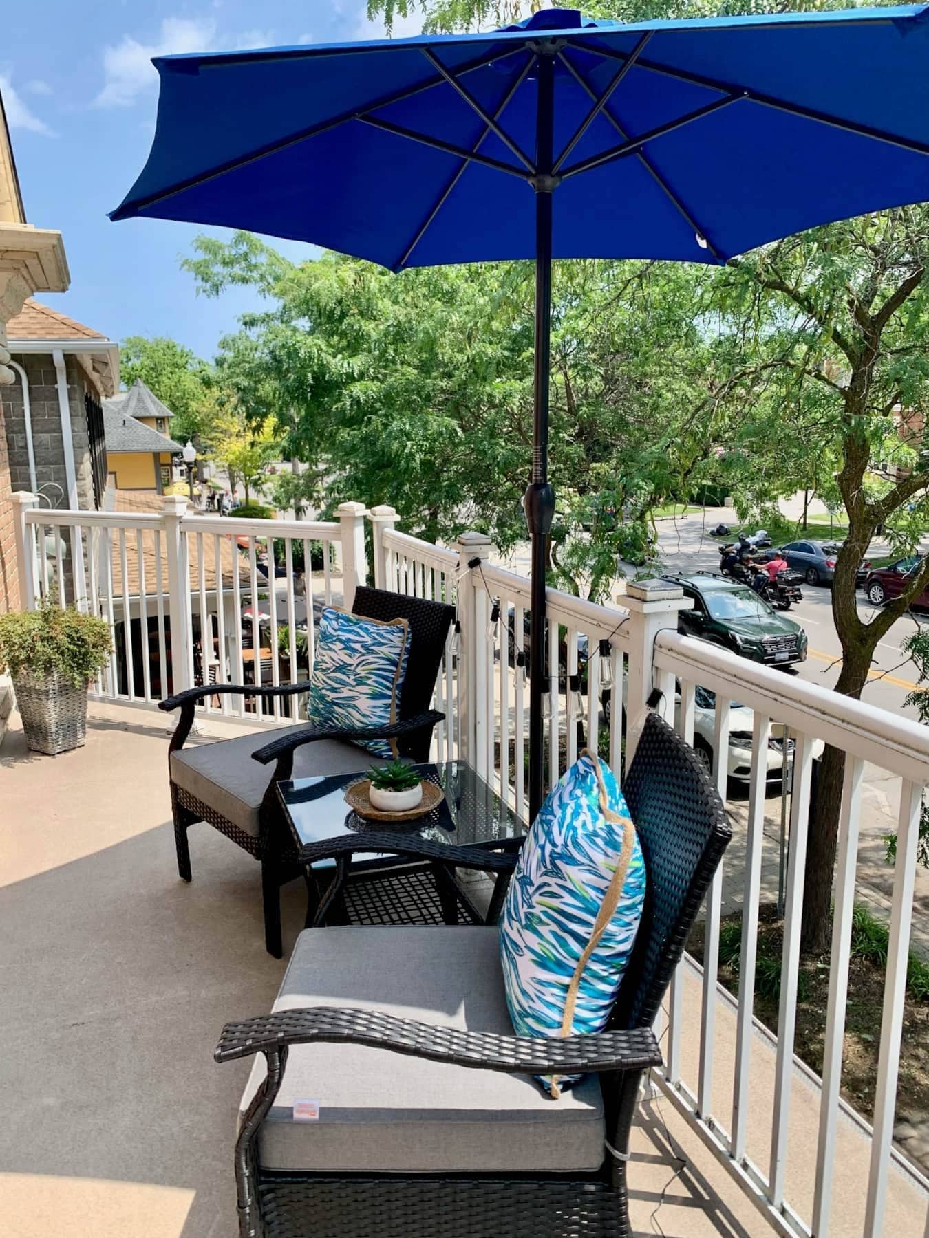 An outdoor seating area with wicker furniture, a table, and a blue umbrella.