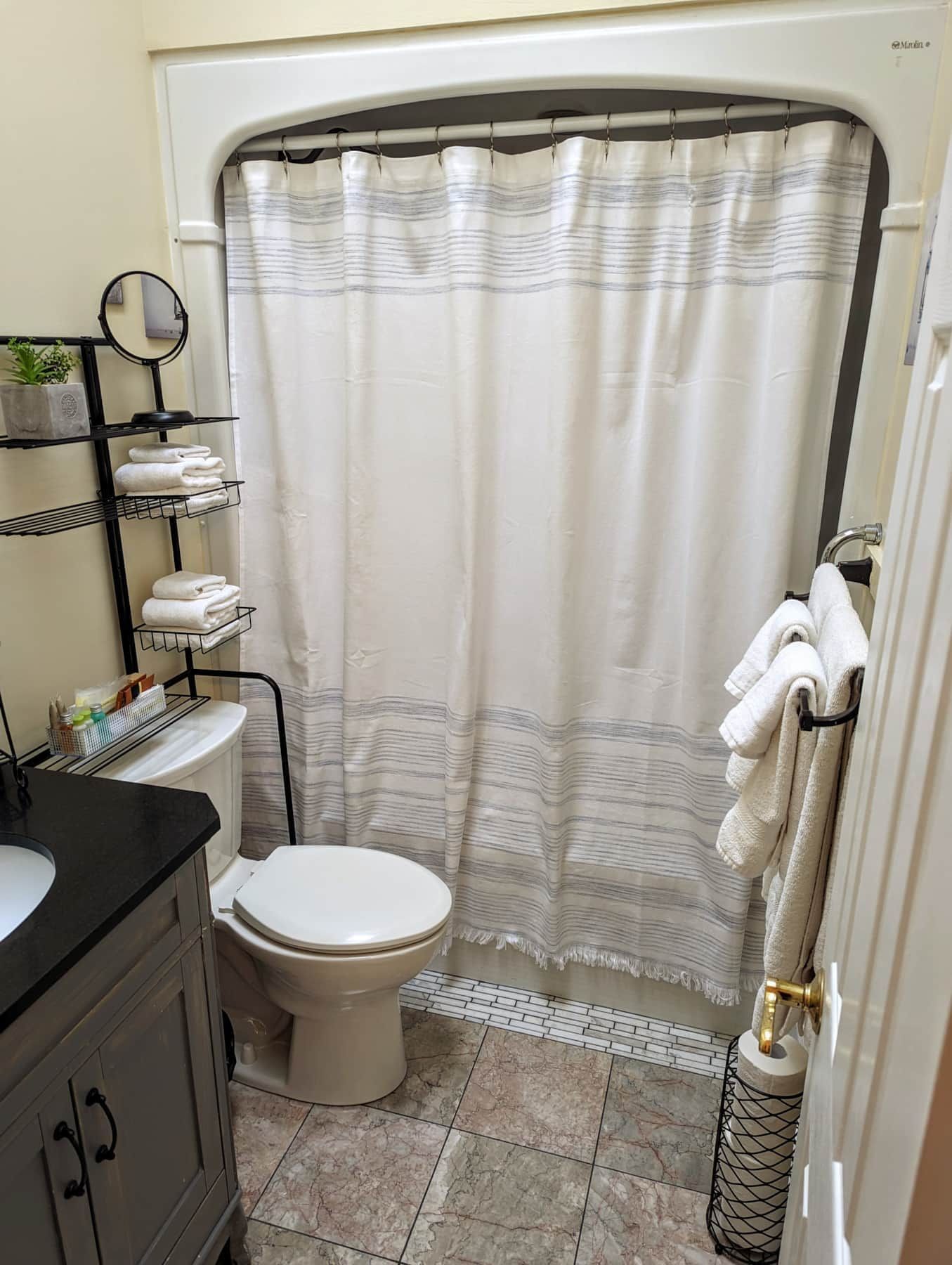 A bathroom with a toilet, a sink, a towel rack, and a shower curtain.