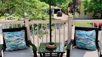 A balcony with two chairs, a small table, and a blue umbrella.