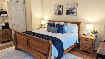 Un dormitorio con una cama de madera, dos mesitas de noche con lámparas, un armario y arte abstracto en la pared.