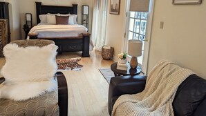 Une chambre à coucher avec un lit, une table de chevet avec une lampe, une chaise et une fenêtre avec des rideaux.