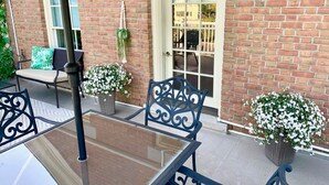 Un espace patio avec une table et des chaises, une porte et des plantes en pot.