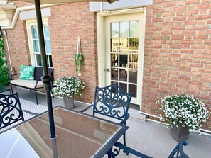 A patio area with a table and chairs, a door, and potted plants. - The Lilibet Suite - Regal and Royal (Niagara-on-the-Lake)