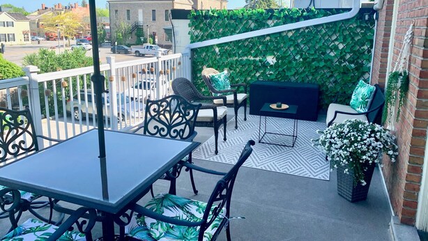 Un balcon équipé d’une table, de chaises, d’un parasol, d’un barbecue et d’un mur décoratif.