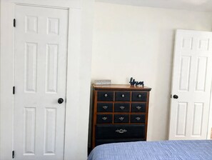 Un dormitorio con cama, cómoda y dos puertas blancas.