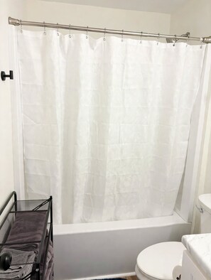 A bathroom with a white bathtub, a white toilet, and a shower curtain.