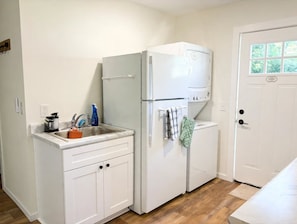 A compact kitchen with a built-in refrigerator, a sink, and a door with a window.