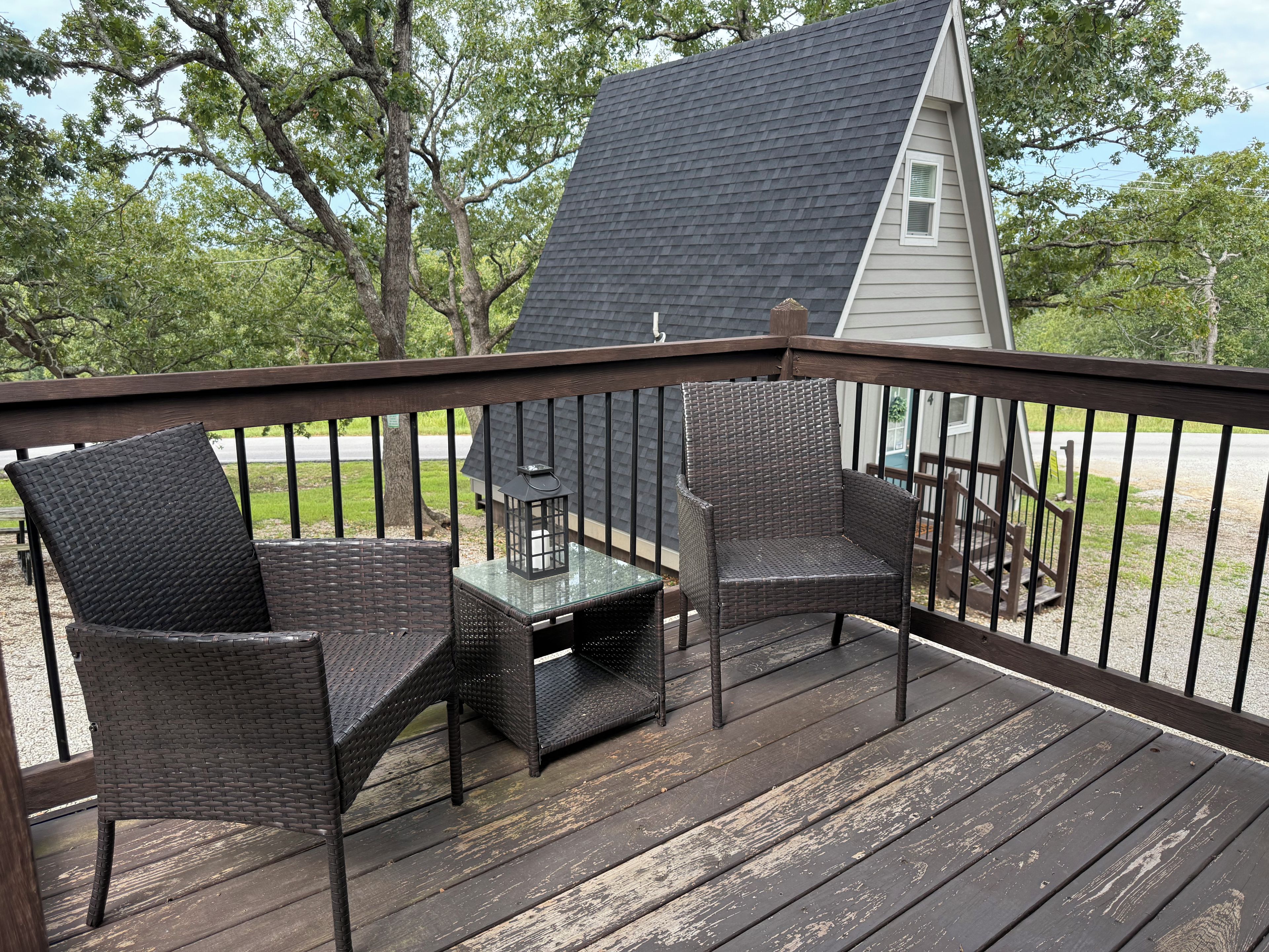 A wooden deck with wicker furniture and a lantern.