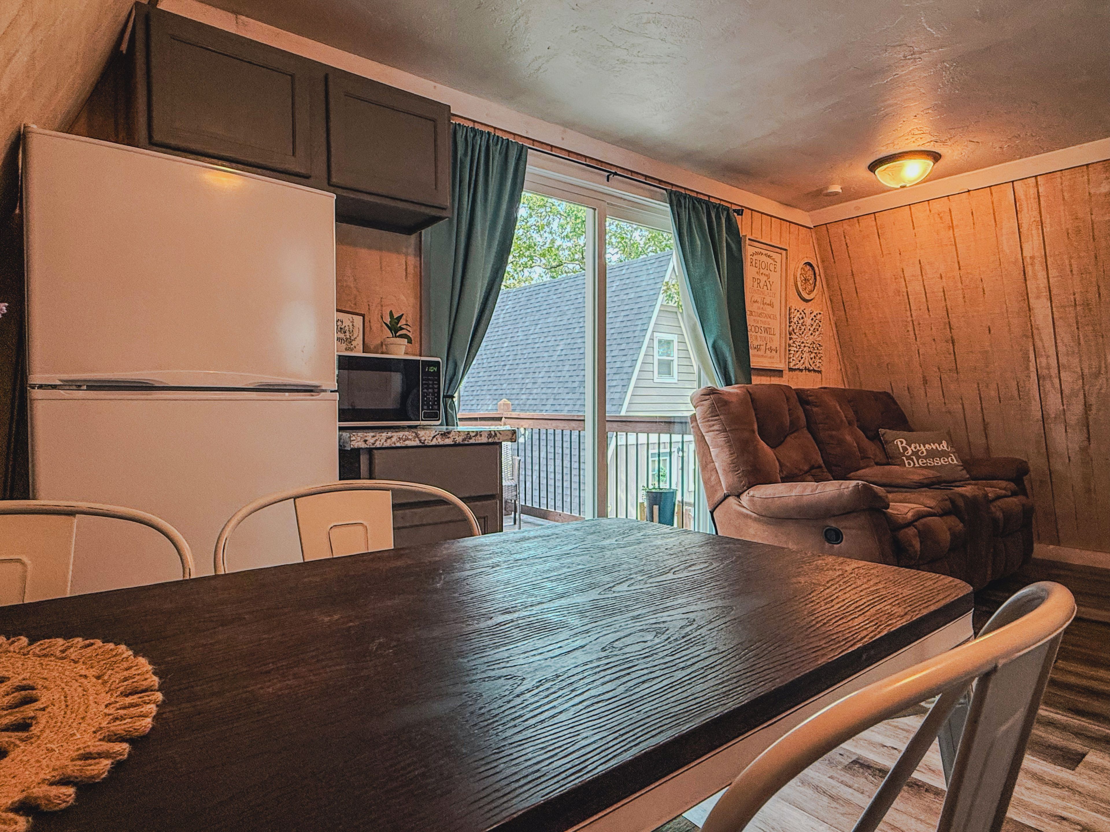 A compact kitchen with a refrigerator, microwave, and a dining table with chairs.